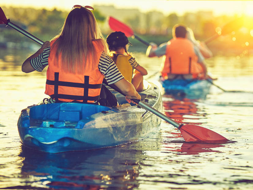 Parents and kids in two kayaks paddling at dusk